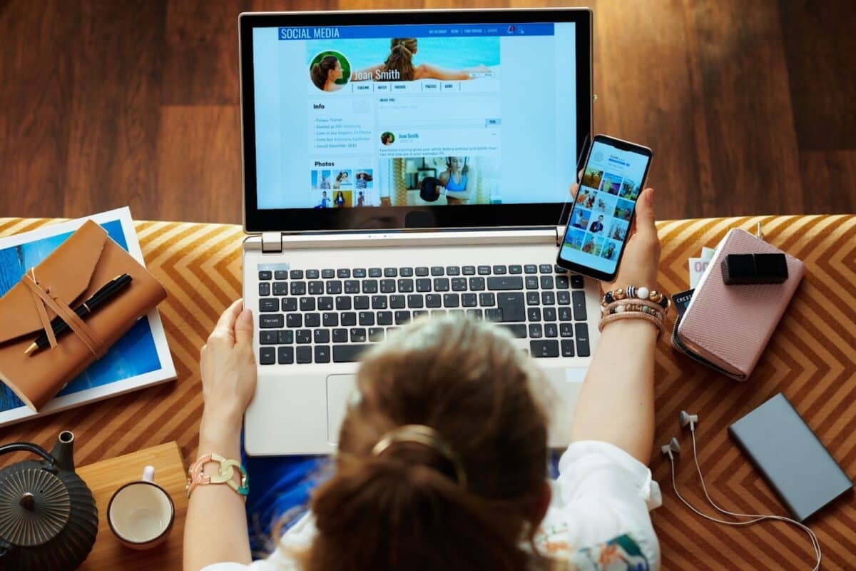 Woman checking social media on smartphone and laptop