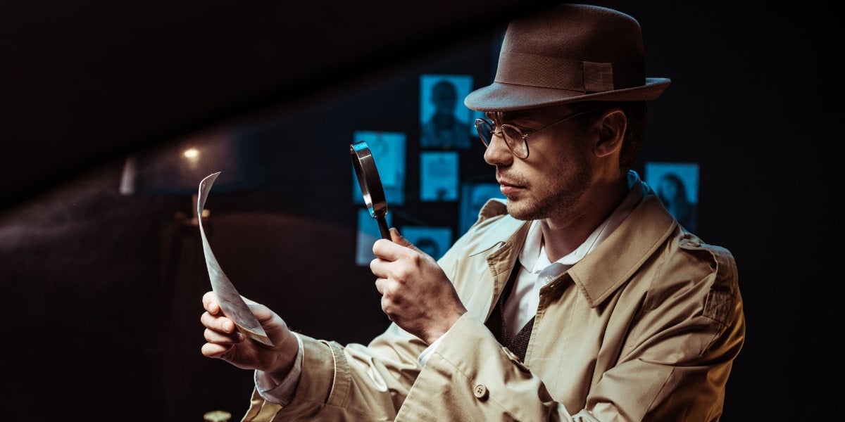 A private investigator looking at a document through a magnifying glass.