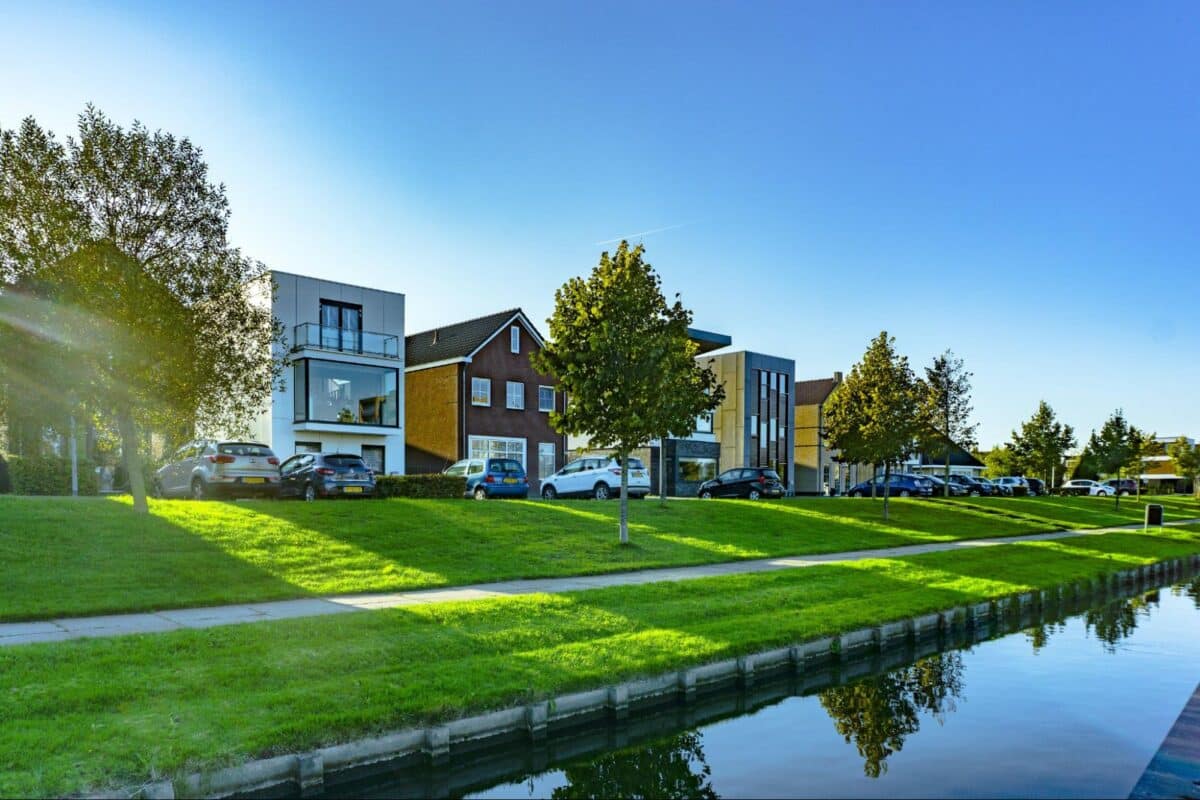 white and brown house near green grass field and body of water during daytime