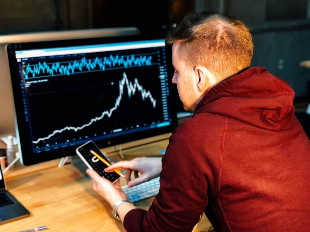 Man holding his smartphone in front of a monitor