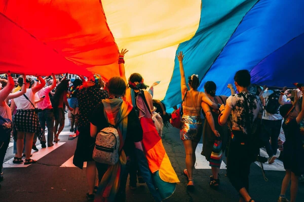 Group of people under a Pride flag during a Pride event