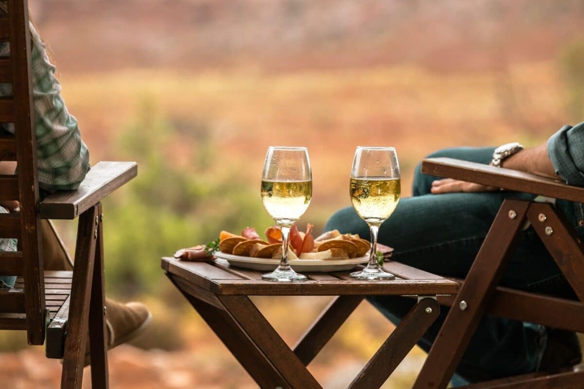 Couple sitting outdoors with a glass of wine and food tray