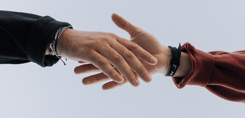 A man and a woman's hands in a handshake symbolizing how real estate agents can take care of distressed homeowners