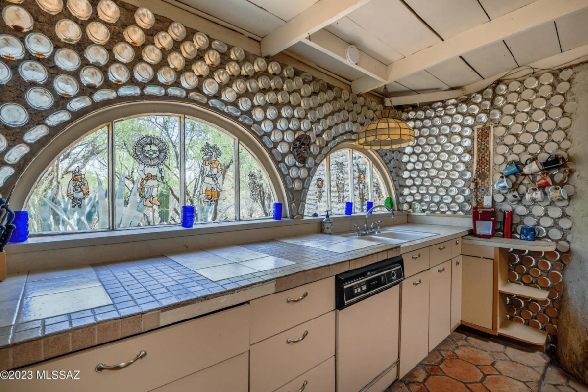 A kitchen's wall covered in beer bottles