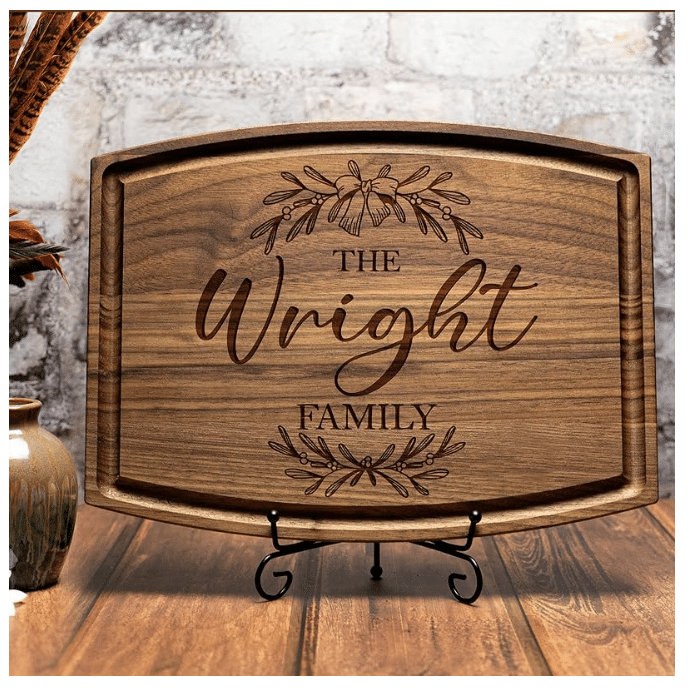 A wooden cutting board with an engraving of family name and design in the center