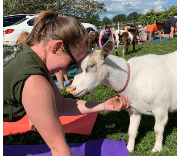 Woman pressing her head against a goat.