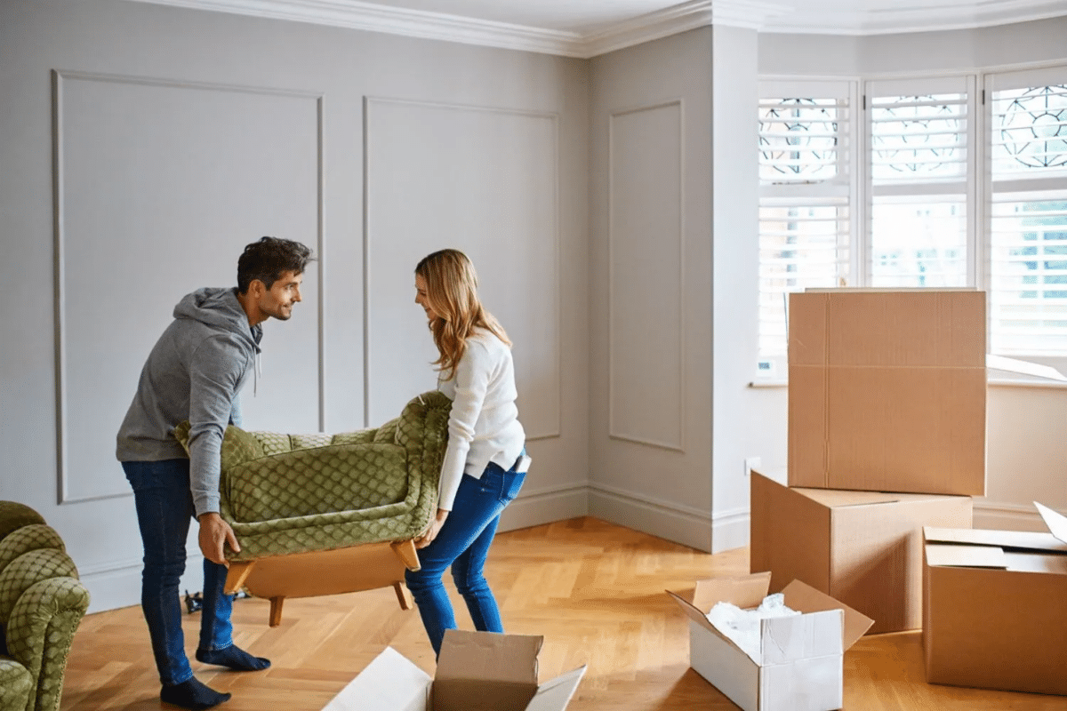 Couple carrying a lounge chair in their new home