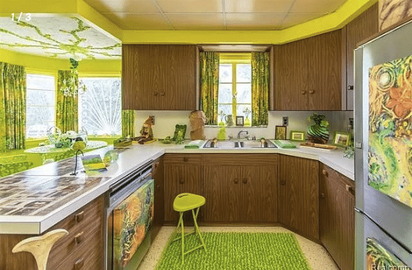 Kitchen with lime green paint around the edging of the ceiling, lime green accessories, a lime colored stool, lime green run on the floor, and lime green floral curtains in the breakfast nook with lime green table and chairs.