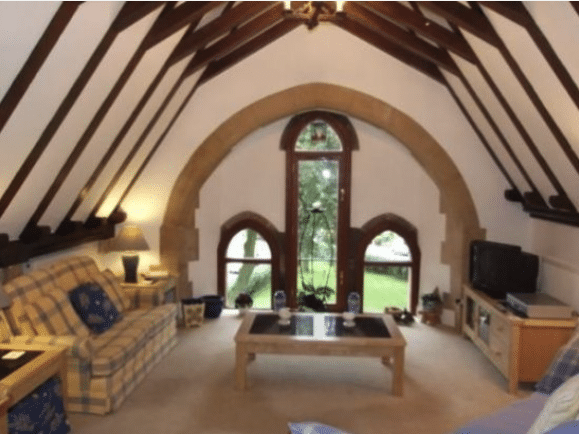 A sitting room with cathedral ceilings and a glass doorway and two side windows.