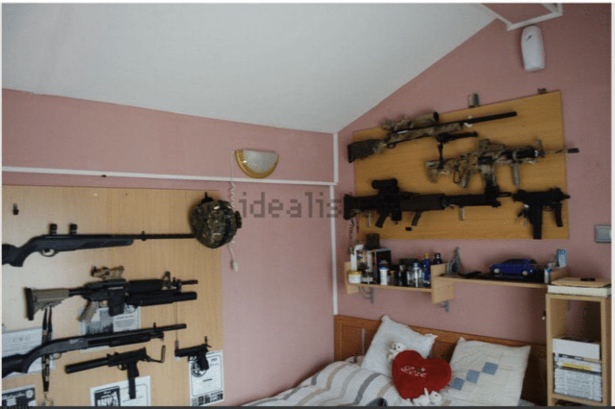 Bedroom with several guns, including rifles, shotguns, and other long guns, hanging on the walls on boards with homemade racks.