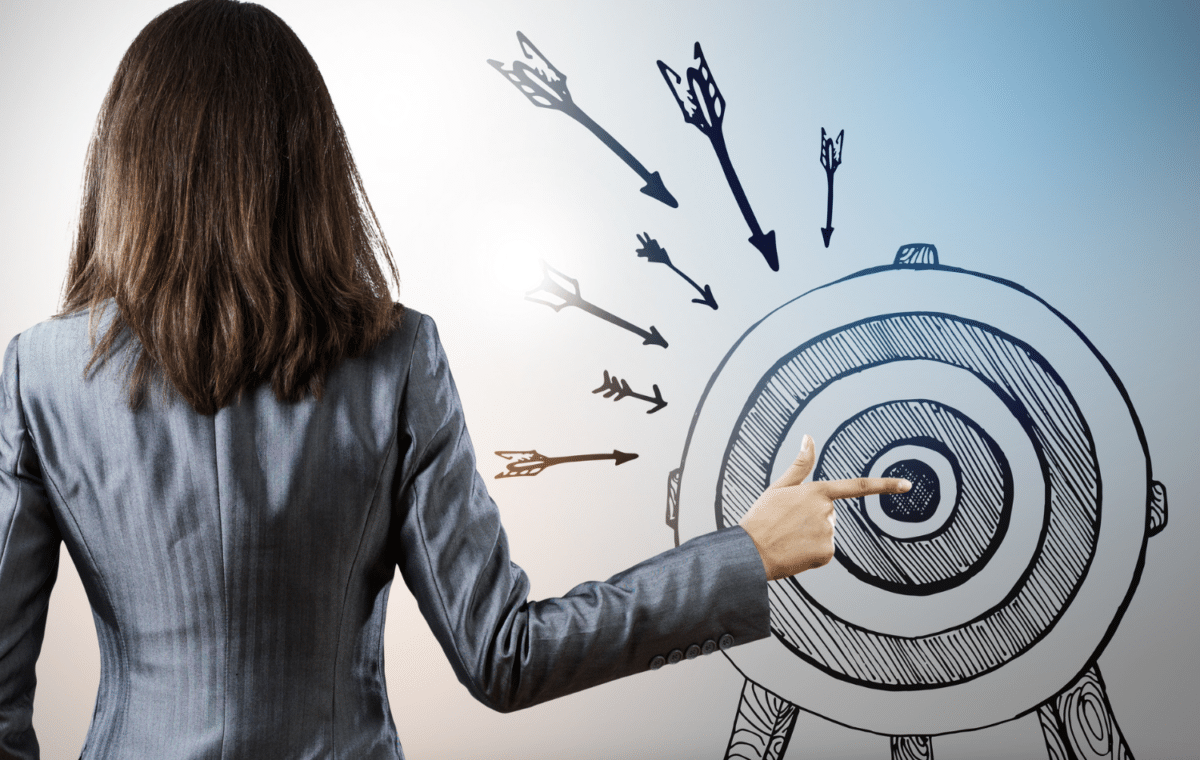 Woman, with her back to the camera, touching the bullseye of an image of an archery target with her index finger