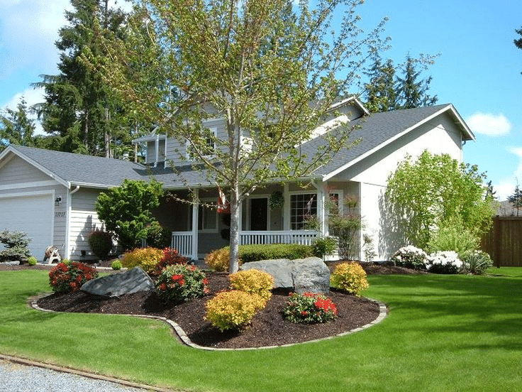 A white house with well-kept and trimmed plants and outside